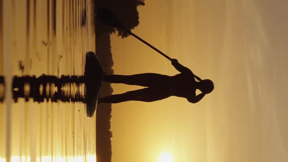 Vertical Screen Woman Paddling on SUP Board at Sunset