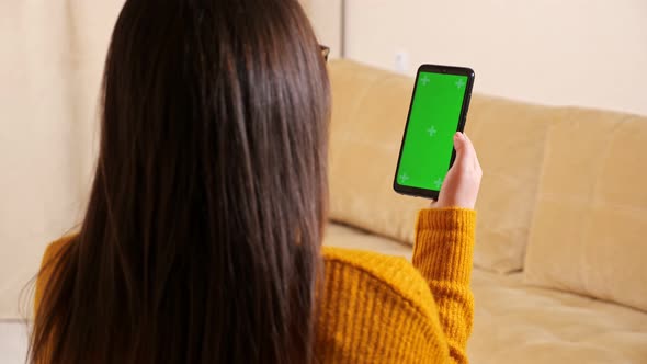 Brunette Holds Black Smartphone with Green Display Backside