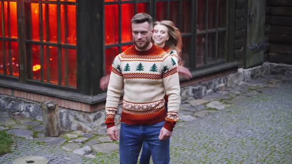 Happy couple outdoors. Young girl jumping on boyfriend's back. 