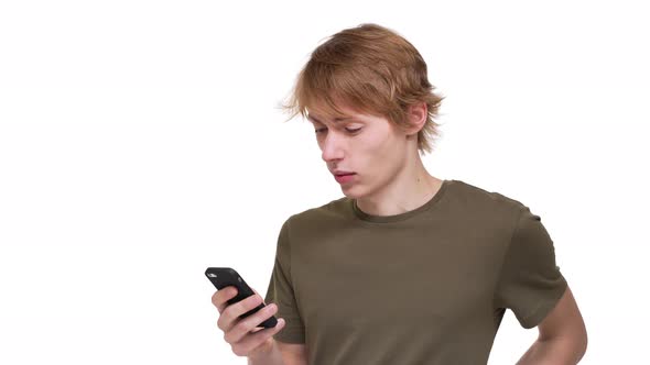 Portrait of Involved Man in Green Tshirt Using Cell Phone Playing Online Games or Chatting Over