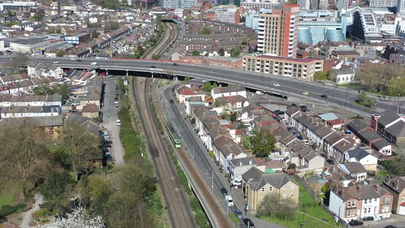 Pan up drone shot from tram and train tracks to croydon town centre London on a sunny day