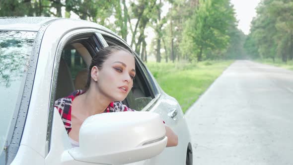 Young Woman Sitting in Her Car Looking Around on Countryside Road