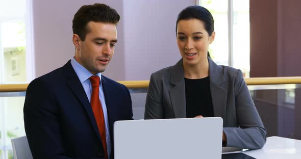 Business people discussing over laptop in conference centre