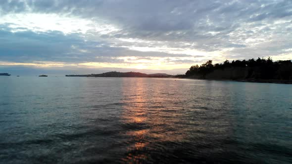 Aerial drone shot at sunset flying low and rising up over the water and reflections of the Pacific O