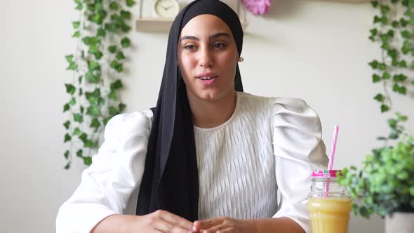 Young woman wearing headscarf sitting at home talking