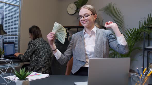 Smiling Young Business Woman Waving with Stack of Money Dollar Cash at Office Desk Workplace