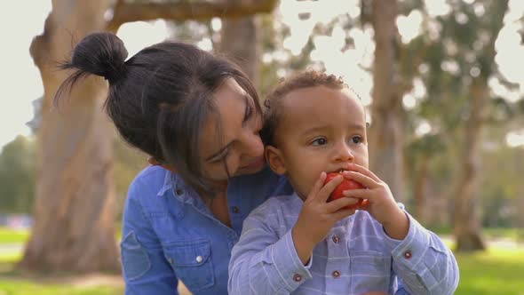 Mother Hugging Son, Looking Him Eating Apple, Caressing Him