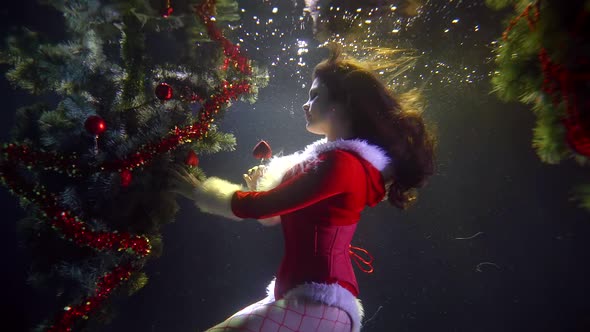 Pretty Brunette Girl Is Decorating Christmas Tree Underwater in Pool, Unusual Celebration