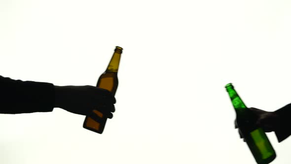 Two Bottles in Different Hands Clink. Silhouette White Background