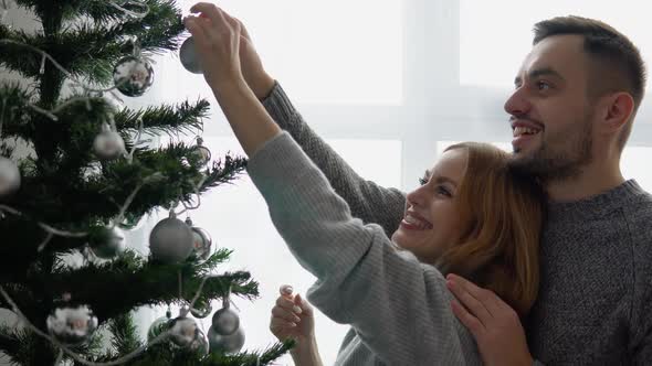 Couple Decorating the Christmas Tree Together in the Christmas Eve