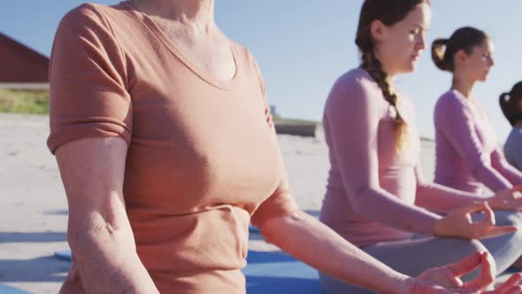 Multi-ethnic group of women doing yoga position on the beach and blue sky background