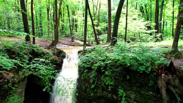 A cinematic view of Cascade falls among leaves and moss covered boulders in Nelson Ledges State Park