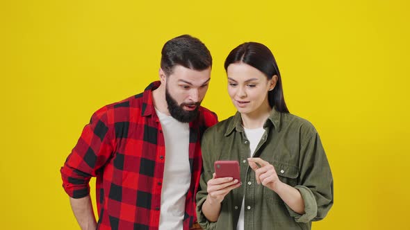 Couple of Students a Man and a Woman Look at the Smartphone Screen and Rejoice