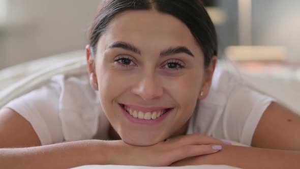 Portrait of Latin Woman Laying in Bed Smiling at Camera