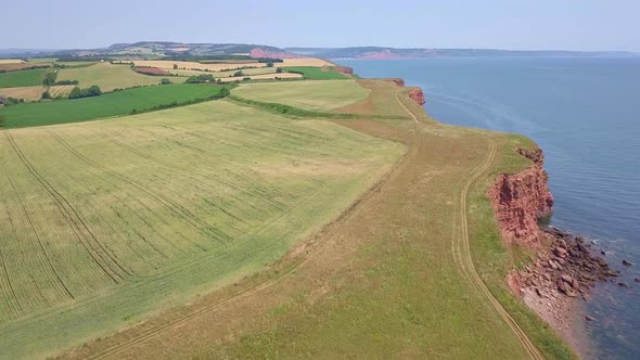 4K Aerial, flying over coastal fields at a UK summer beach town