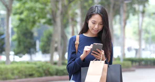 Shopping woman holding paper bag and use of cellphone