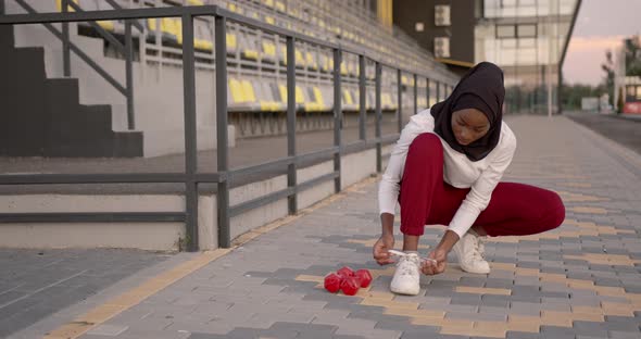 Muslim Black Woman Putting Up Laces at Stadium