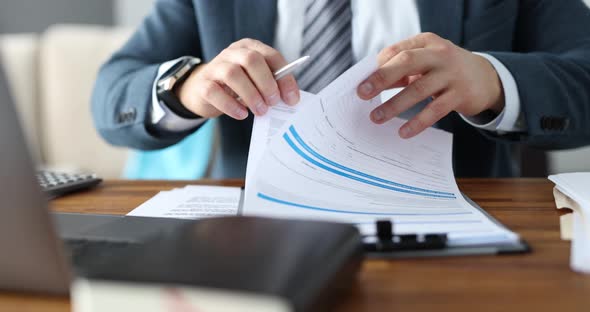 Businessman is Studying Business Document at Workplace Closeup