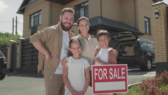 Happy Family Posing before House for Sale