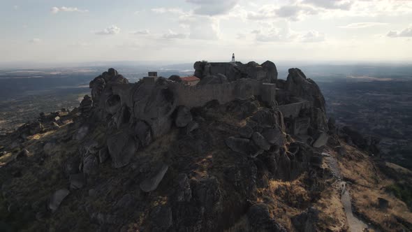 Medieval hilltop castle of Monsanto at sunset; cinematic drone orbit