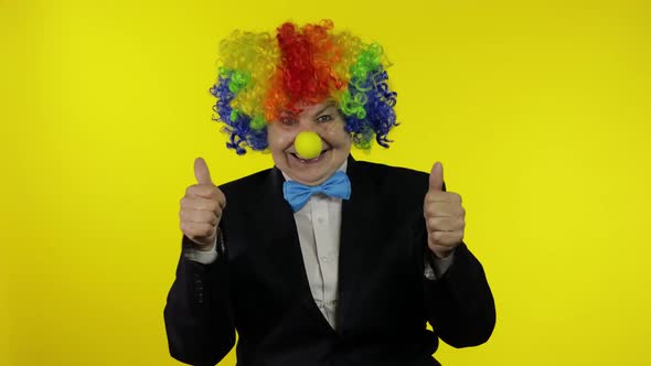 Senior Woman Clown in Wig Having Fun, Smiling, Waves Her Hands, Show Thumb Up