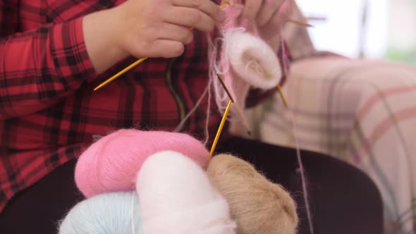 An Adult Woman Knits From a Thin Yarn