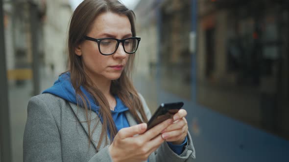 Woman Stands at a Public Transport Stop and Checks the Timetable