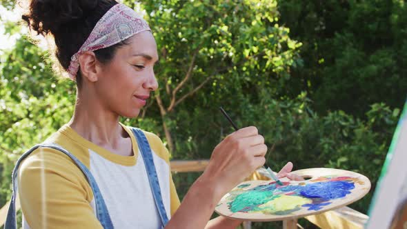 Mixed race woman painting on canvas in the balcony at home