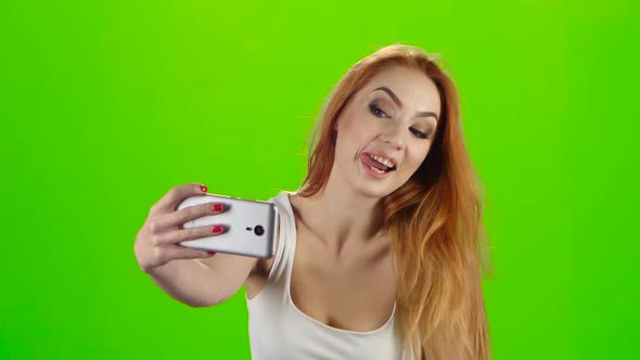 On the Smartphone Camera Redhead Girl Doing Selfie. Green Screen