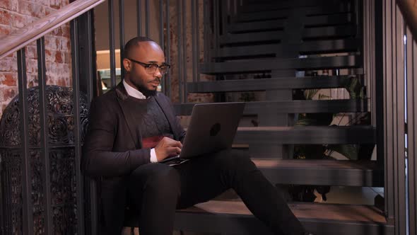 An African American Student Works at a Laptop in a Cafe