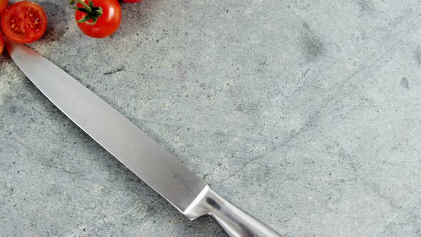 Cherry tomatoes and kitchen knife on concrete