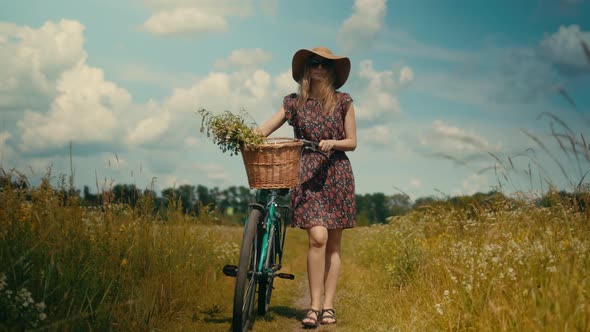 Woman In Hat Enjoying Weekend.Woman Cyclist Walking With Bike On Holiday Vacation Trip. Wildflower.