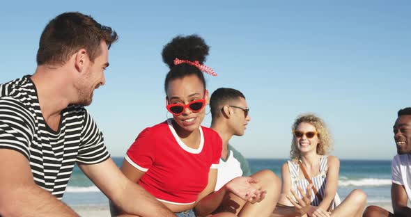 Young adult friends sitting on a beach talking 4k