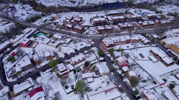 High angle birdseye view over the homes and buildings of Pradera de Navalhorno on a chilly snow-cove