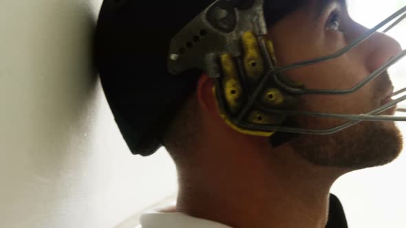 Cricket player sitting with his head leaning against wall in dressing room