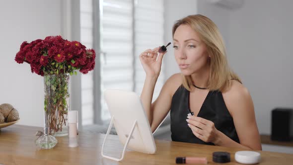 Beautiful Young Woman Applies Makeup. The Blonde Paints Her Face To Look Better