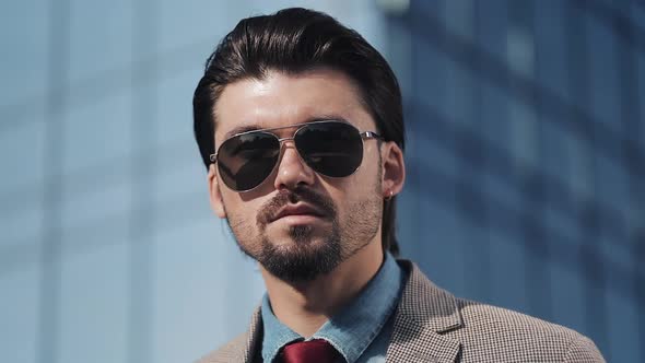 Portrait of Young Handsome Successfull Bussinessman Wearing a Suit and Sunglasses Standing Near