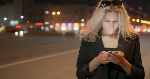 Woman Holds Smartphone in Hands Taps on Screen and Smiles