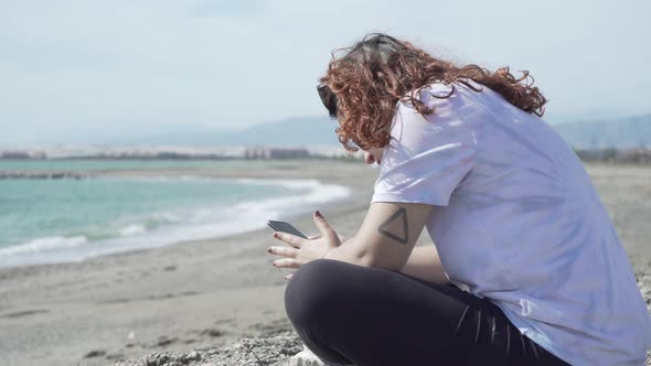 Young Woman With Phone On Beach