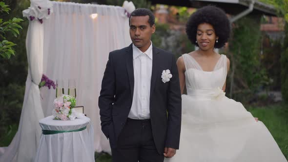 Handsome Confident Groom in Suit Standing Outdoors As Bride Approaching Taking Hand of Partner