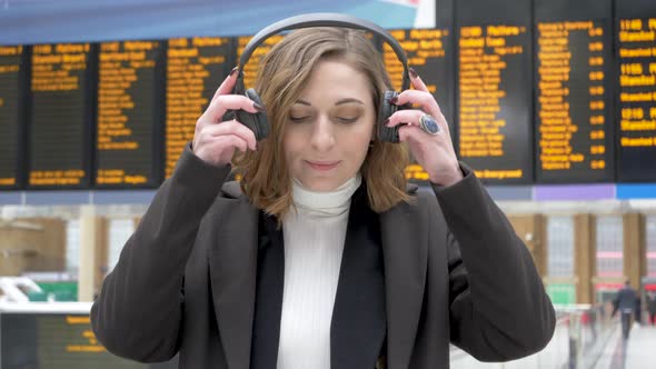Young woman using headphones at station