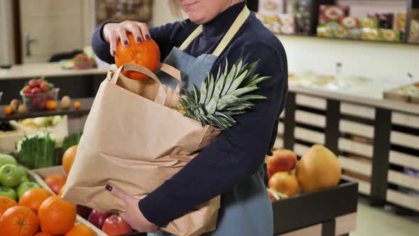 Young Saleswoman Collects Vegetables and Fruits in a Paper Bag