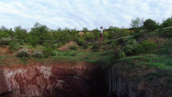 Aerial Footage of Man Slacklining Standing on Rope Over the Pit Film Grain