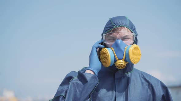 Professional Virologist in Biohazard Suit and Respirator Talking on Phone. Portrait of Confident