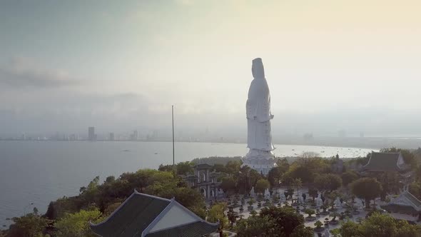 Motion Down From Statue To House Among Trees Against Ocean