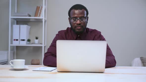 Businessman Working with Laptop and Posing for Camera at Table in Modern Office Spbas