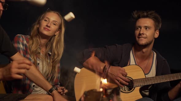 Young Handsome Caucasian Male Playing Guitar Smiling While Blonde Beautiful Female Listening