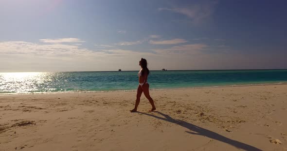 Beautiful happy lady on photoshoot spending quality time at the beach on summer white sand and blue 