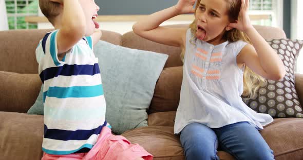 Boy and girl sitting on sofa teasing each other