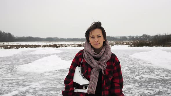 Woman standing with skates on frozen lake